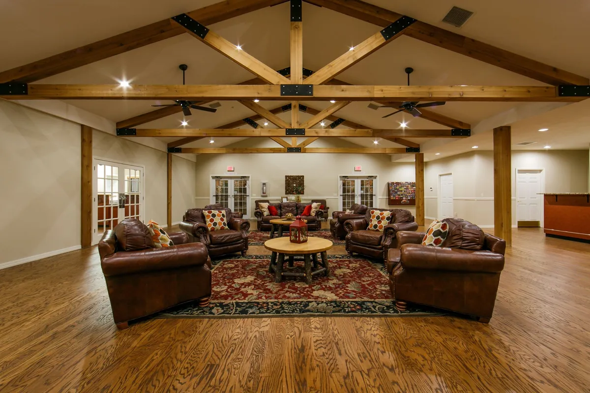 A spacious living area with exposed wooden beams, comfortable leather sofas, a stylish coffee table, decorative pillows, and a cozy rug. The arrangement is perfect for family bonding, social gatherings, or casual conversations in a welcoming atmosphere.